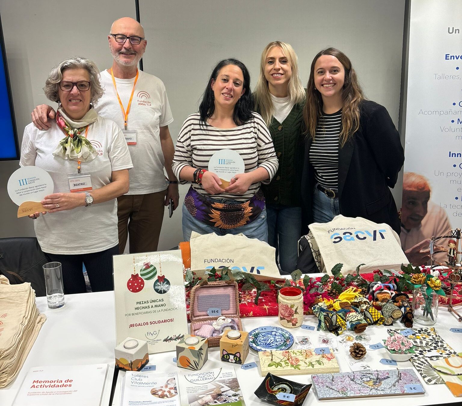 Miembros de AMAI TLP y Fundación Alicia y Guillermo posan en el mercadillo de Fundación Sacyr