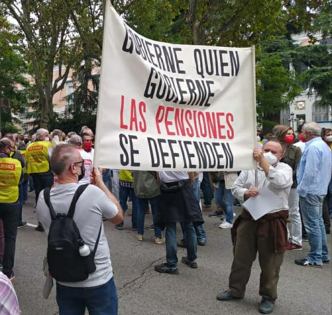 dos hombres sujetan una pancarta en la manifestación por la defensa del sistema público de pensiones