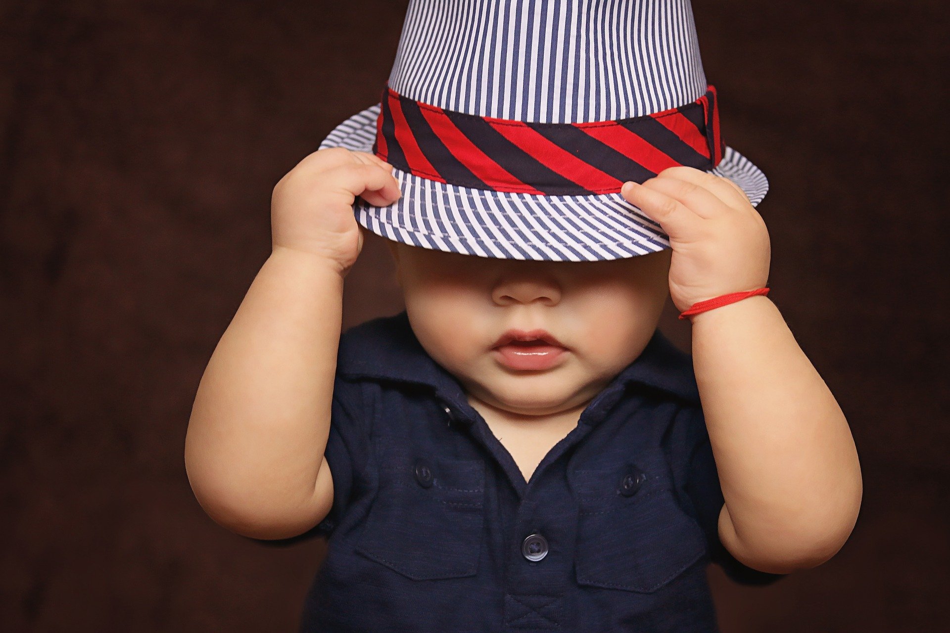 niño se tapa la cara con un sombrero