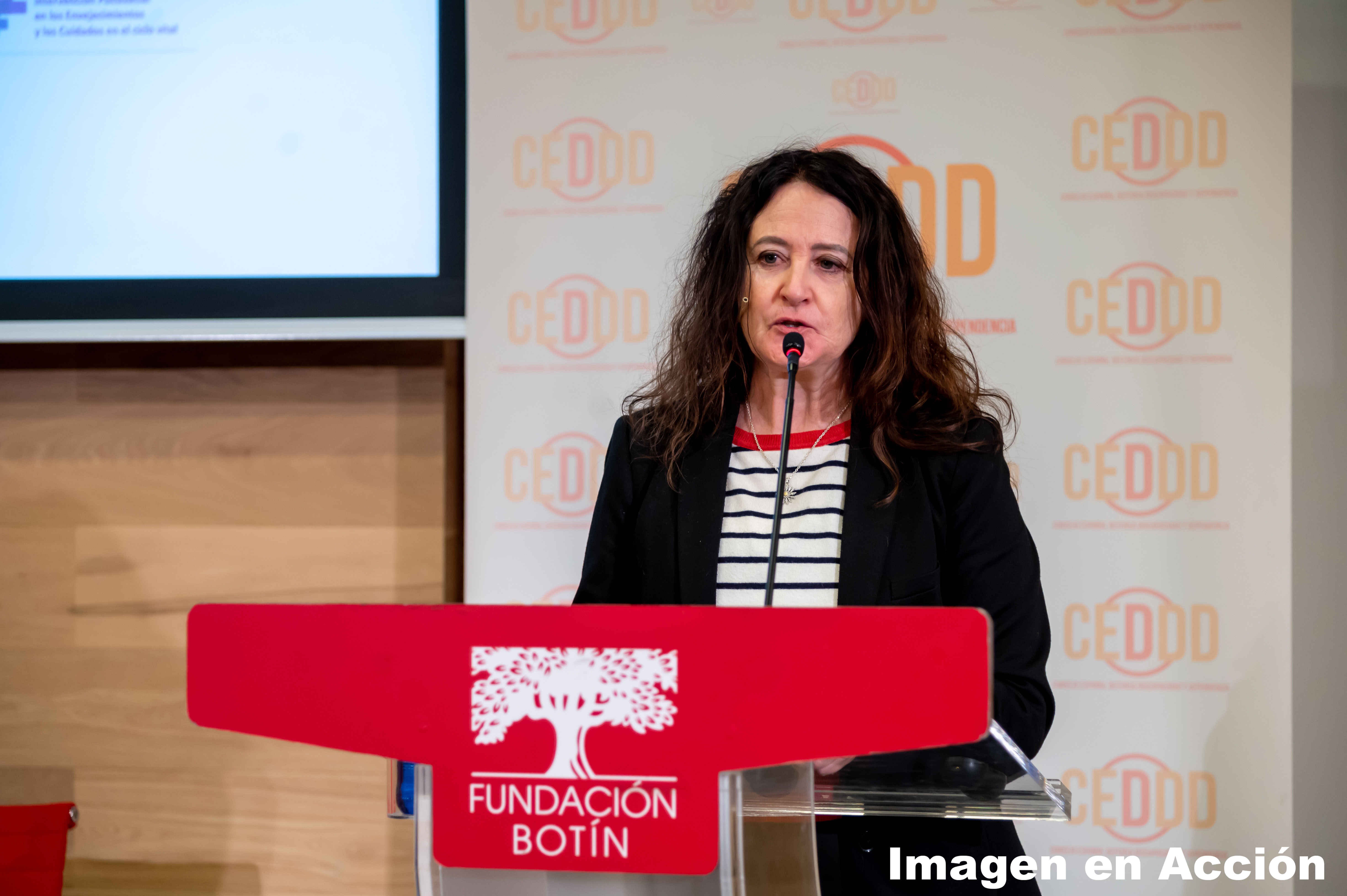 una mujer de pelo largo, ante un atril