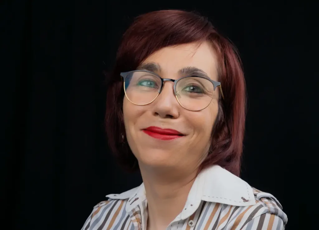 una mujer con camisa a rayas, gafas y brazos cruzados