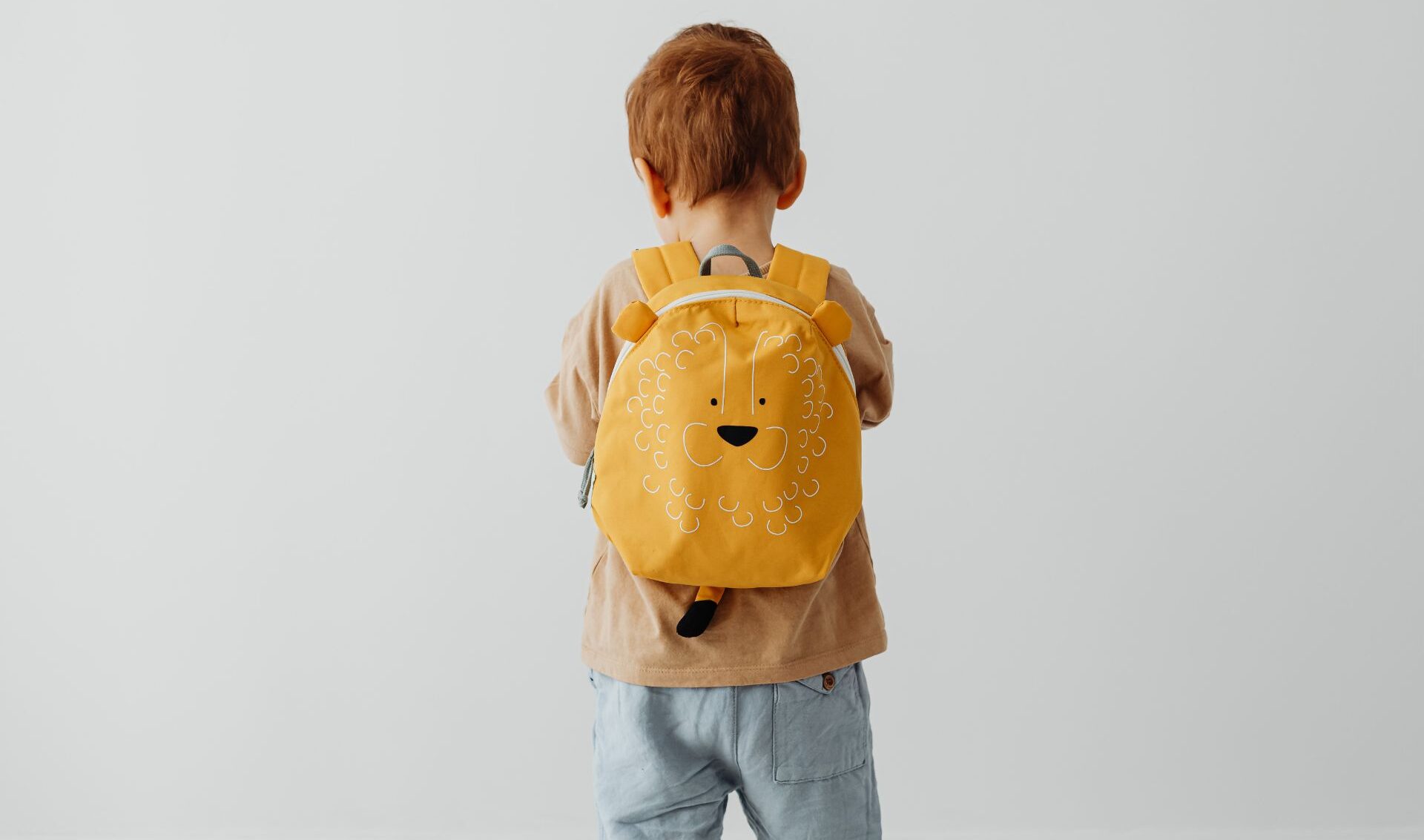 Niño con mochila de espaldas, está sólo.