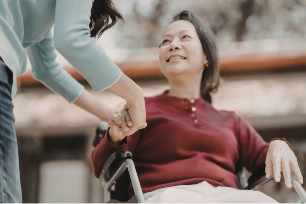 Mujer en silla de ruedas es asistida por otra.