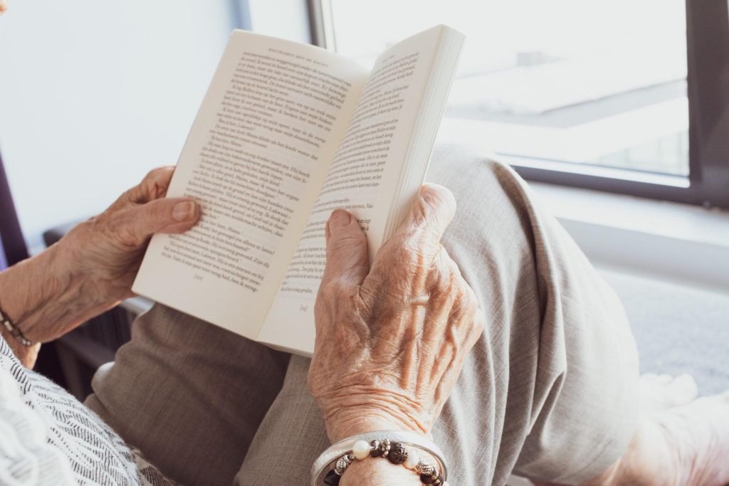 primer plano de las manos de una persona mayor leyendo un libro